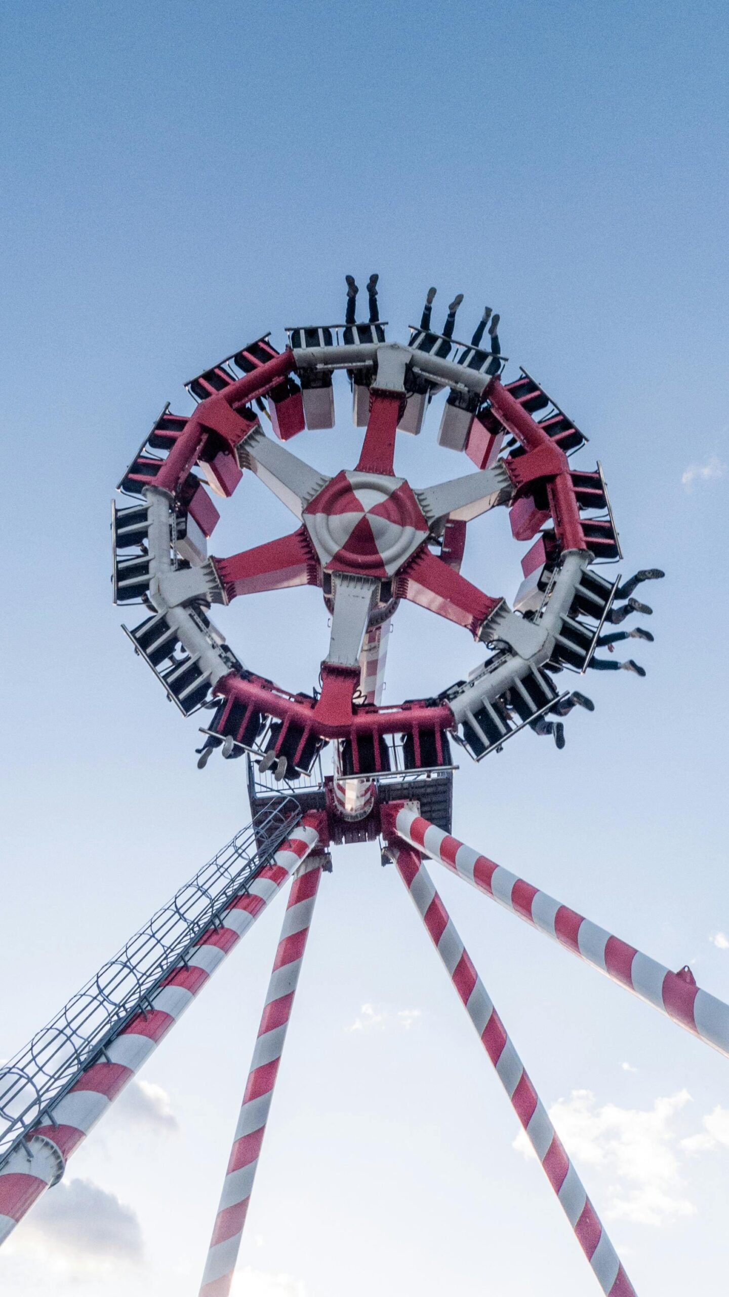 Exciting pendulum ride at theme park captured from below, set against a clear blue sky.